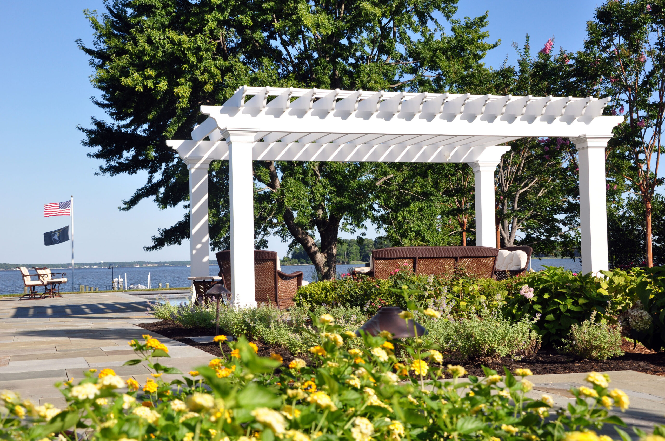 Waterfront pergola with wicker seating, lantana garden beds, and Chesapeake Bay views designed by McHale Landscape Design