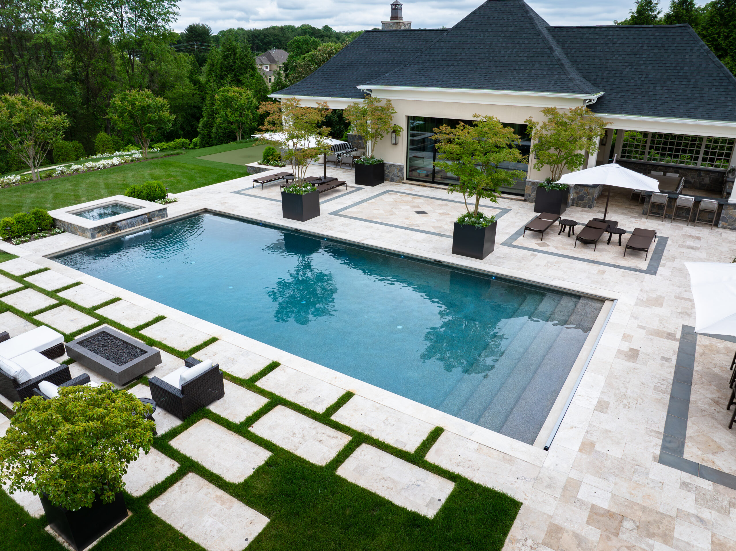 Aerial view of luxury pool and travertine terrace with spa, fire pit seating, and poolhouse at Hunter Mill Residence by McHale Landscape Design